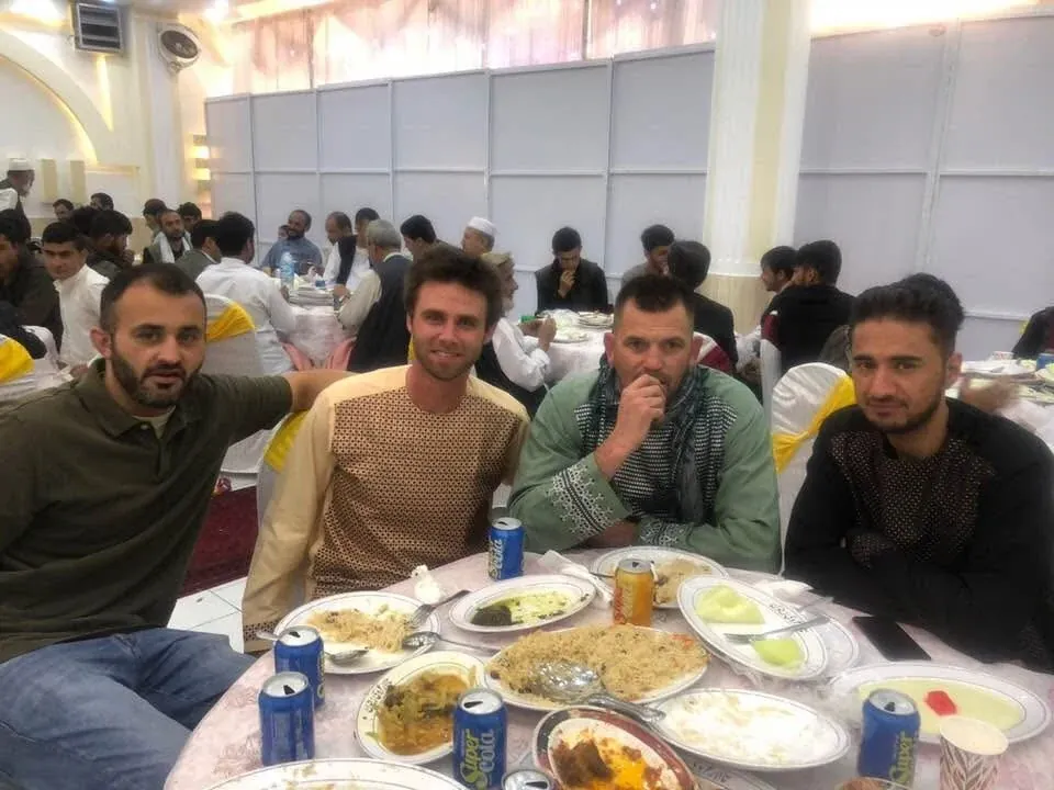 Guests at a wedding table set with rice, side dishes and canned drinks